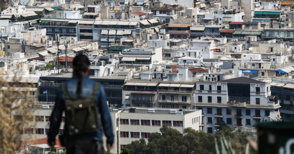 Γυναίκα κοιτάει πανοραμικά τα σπίτια στην Αθήνα από λόφο