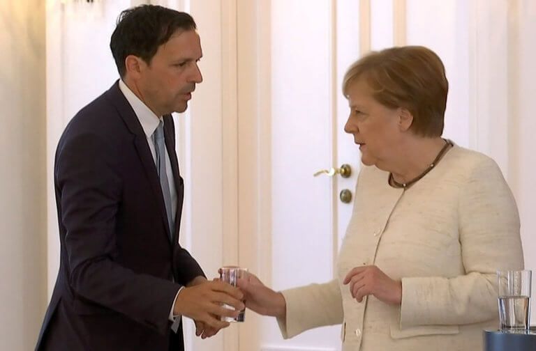 merkel-nero.jpg Υπάλληλος της προεδρίας προσφέρει νερό στην Άγκελα Μέρκελ