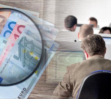 Χρήματα σε ευρώ, μεγεθυντικός φακός και υπάλληλοι σε υπολογιστές