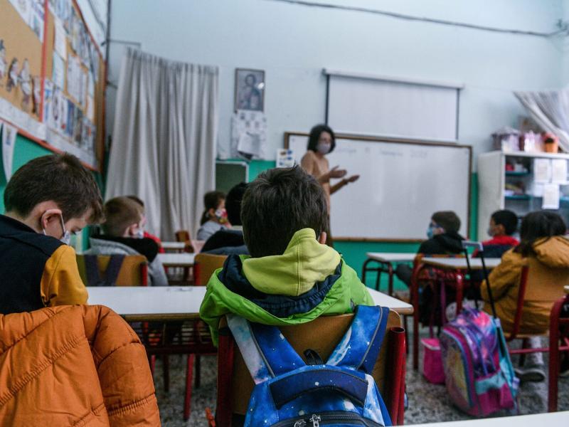 Σχολική τάξη, μαθητές σε θρανία και στο βάθος η δασκάλα τους μιλάει