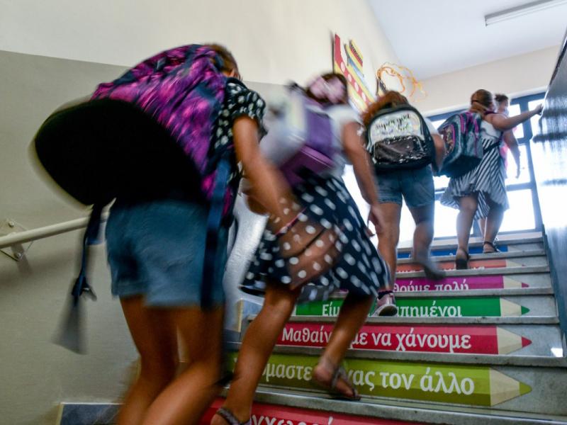 Μαθητές τρέχουν σε σκάλα σχολείου με τσάντες