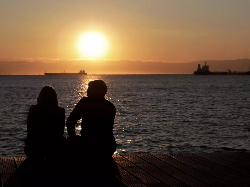 Ζευγάρι κοιτάει το ηλιοβασίλεμα στη θάλασσα