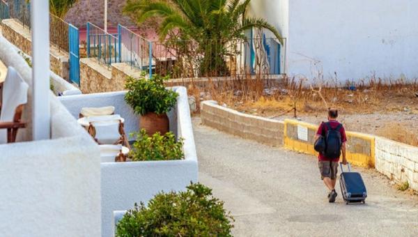 Άνδρας περπατάει με βαλίτσα στο χέρι σε νησί