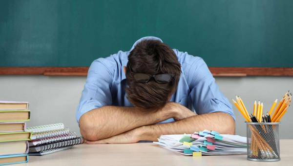 Δάσκαλος κουρασμένος ξαπλώνει πάνω στα χέρια του στην έδρα