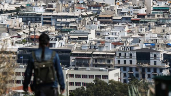 Γυναίκα κοιτάει πανοραμικά τα σπίτια στην Αθήνα από λόφο