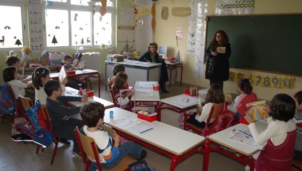 Αίθουσα σχολείου με μαθητές στα θρανία και δασκάλα