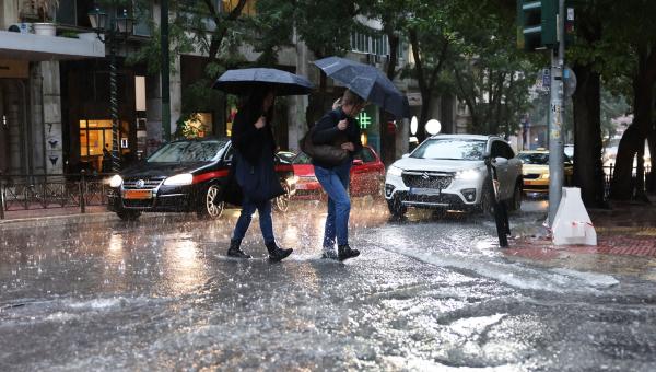 κακοκαιρία, ΕΜΥ, άνθρωποι με ομπρέλες προχωρούν σε πλημμυρισμένο δρόμο