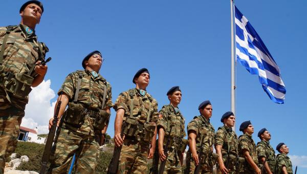 Στρατιώτες, φαντάροι σε στάση προσοχής με φόντο την ελληνική σημαία