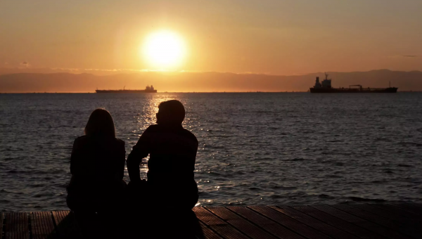 Ζευγάρι κοιτάει το ηλιοβασίλεμα στη θάλασσα