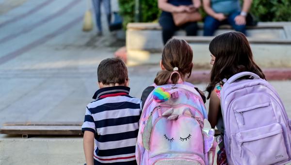 Μαθητές με σχολική τσάντα κάθονται και μιλάνε