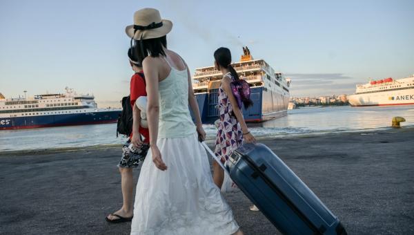 Γυναίκες κρατάνε βαλίτσες στο λιμάνι και πηγαίνουν διακοπές