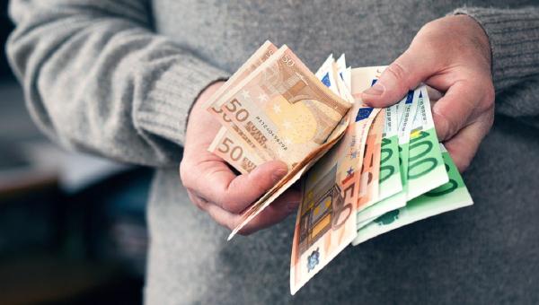 Άνδρας μετράει χρήματα και ευρώ με τα χέρια του