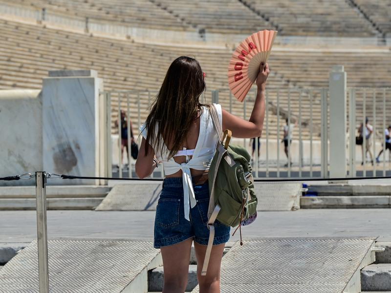 Κοπέλα κάνει αέρα με βεντάλια έξω από το παναθηναικό στάδιο λόγω καύσωνα