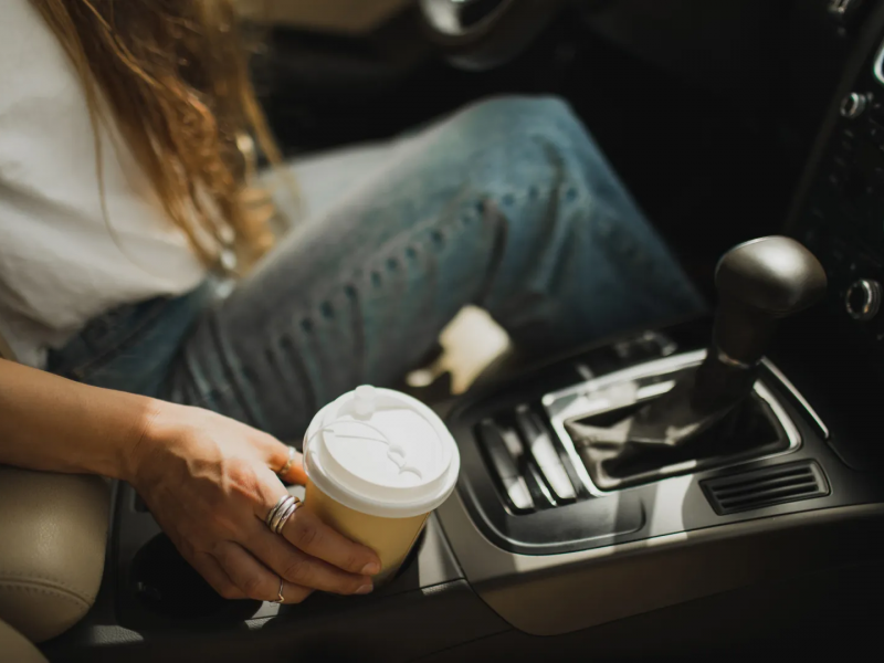 Γυναικείο χέρι κρατάει καφέ μέσα σε αμάξι