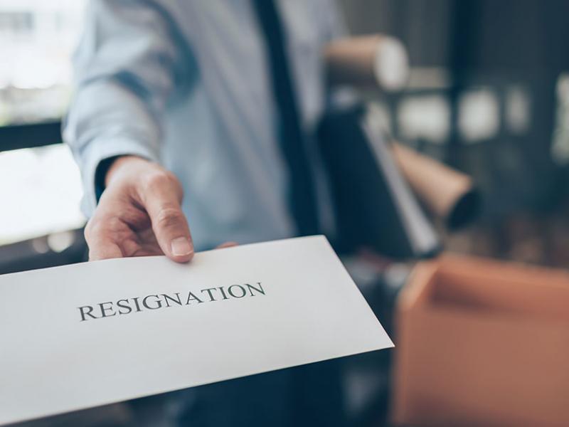 Χέρι ανθρώπου με κοστούμι δίνει φάκελο προς την κάμερα με την αναγραφή resignation