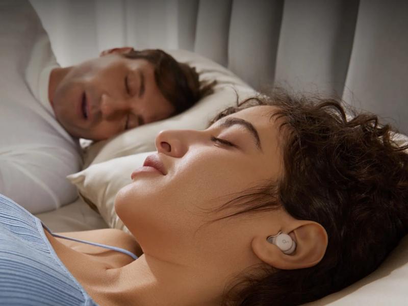 Γυναίκα κοιμάται δίπλα στον άντρα της και φοράει ακουστικά