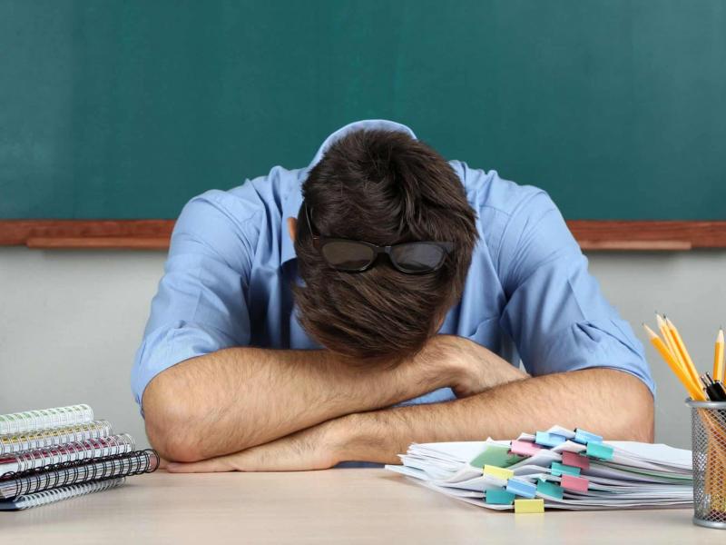 Δάσκαλος κουρασμένος ξαπλώνει πάνω στα χέρια του στην έδρα