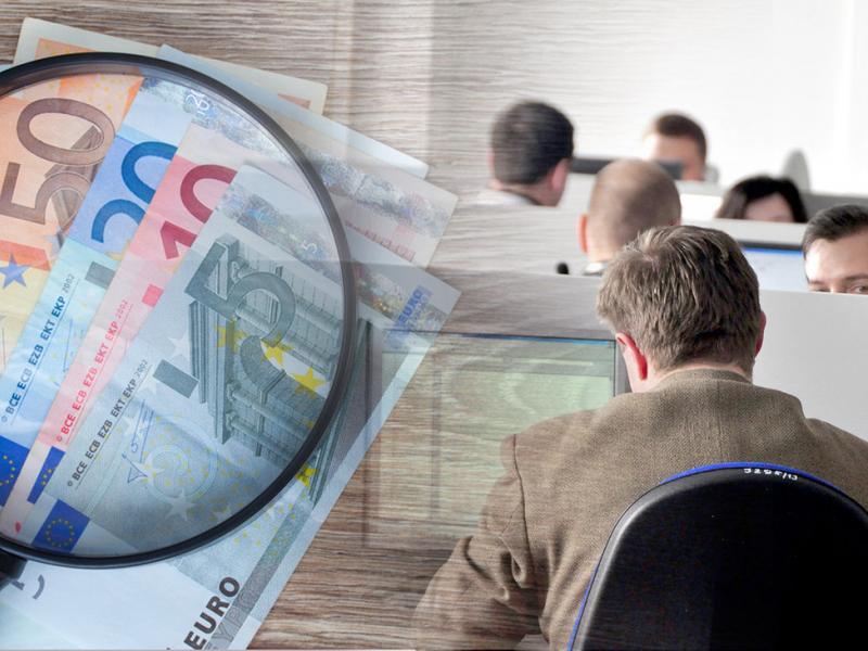 Χρήματα σε ευρώ, μεγεθυντικός φακός και υπάλληλοι σε υπολογιστές