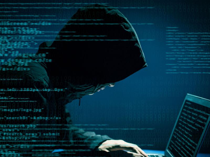 Χάκερ με κουκούλα σε υπολογιστή με δεδομένα στην οθόνη