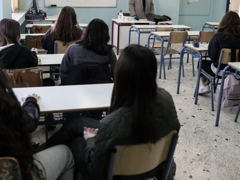 μαθητές σε τάξη κάθονται στα θρανία και έχουν πλάτη στην κάμερα