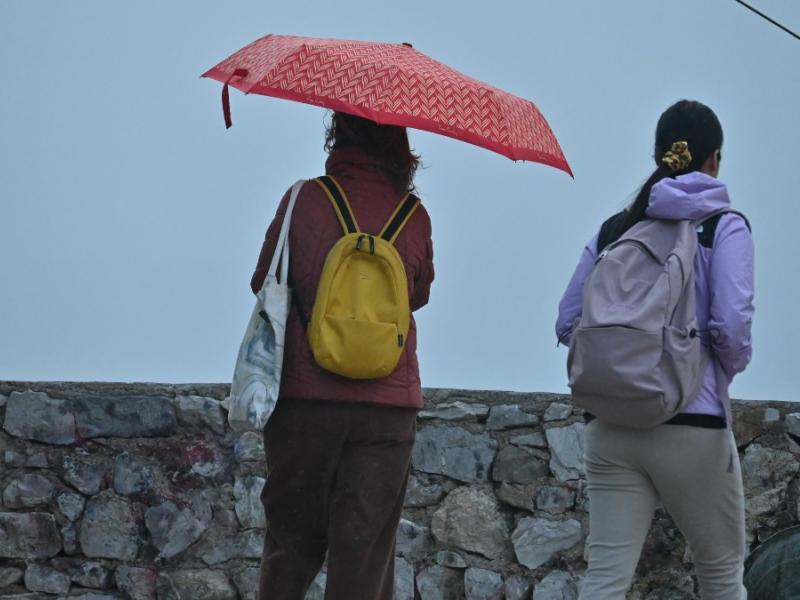 κακοκαιρία, καιρός και γυναίκες κρατούν ομπρέλες στη βροχή