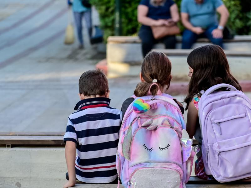 Μαθητές με σχολική τσάντα κάθονται και μιλάνε