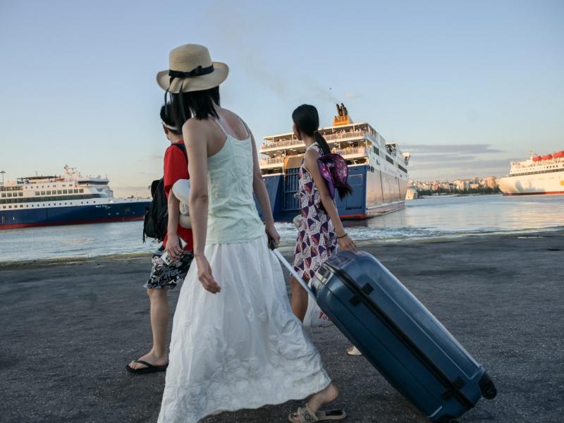 Γυναίκες κρατάνε βαλίτσες στο λιμάνι και πηγαίνουν διακοπές