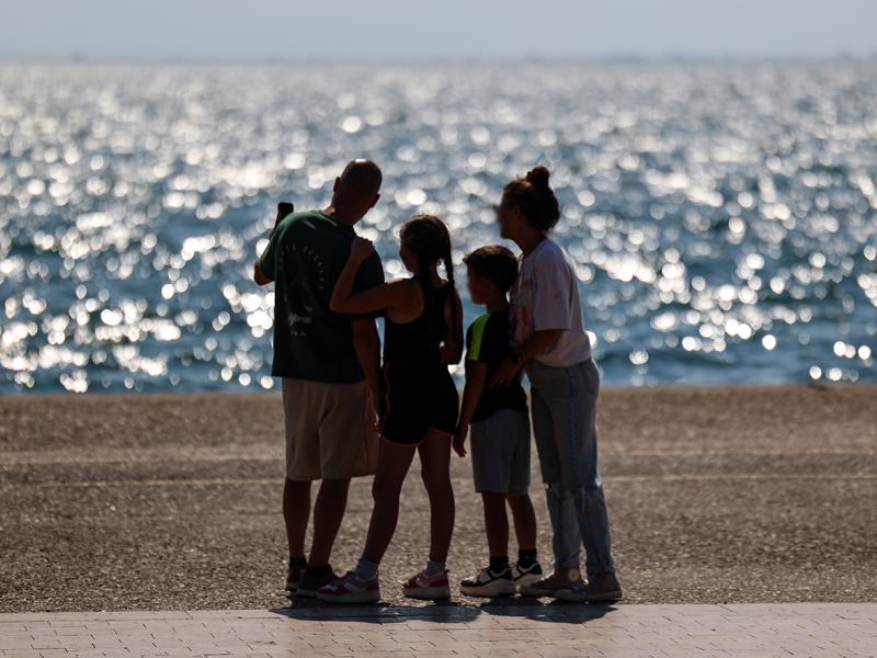 Οικογένεια που θα πάρει το έκτακτο επίδομα παιδιού κοιτάζει τη θάλασσα αγκαλιά