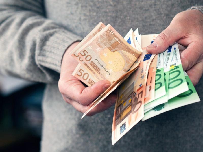 Άνδρας μετράει χρήματα και ευρώ με τα χέρια του