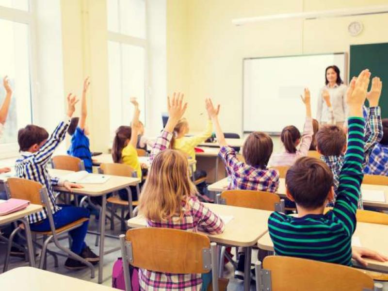 group-of-school-kids-with-teacher-sitting-in-classroom-and-raising-hands_0_0.jpg