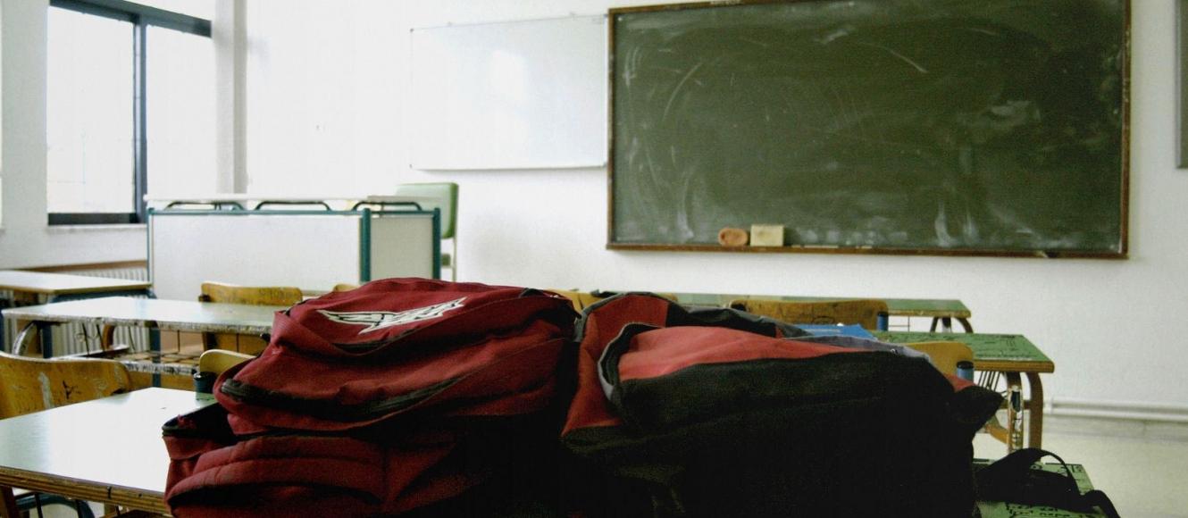 Άδεια σχολική τάξη με τσάντες πάνω σε θρανίο 