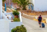 Άνδρας περπατάει με βαλίτσα στο χέρι σε νησί