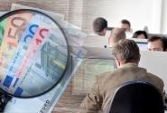 Χρήματα σε ευρώ, μεγεθυντικός φακός και υπάλληλοι σε υπολογιστές