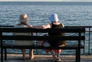 Γυναίκες συνταξιούχοι κάθονται σε παγκάκι και κοιτάνε τη θάλασσα το καλοκαίρι