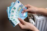 Χέρια μετράνε χρήματα για το επίδομα θέρμανσης δίπλα σε καλοριφέρ