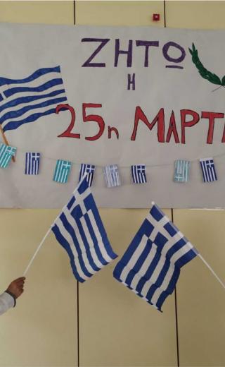 Μαθητές με ελληνική σημαία κοιτάνε πινακίδα που γράφει ζήτω η 25η Μαρτίου