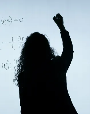 Εκπαιδευτικός γυναίκα γράφει σε ψηφιακό πίνακα και φαίνεται μόνο το περίγραμμα της σκιάς της