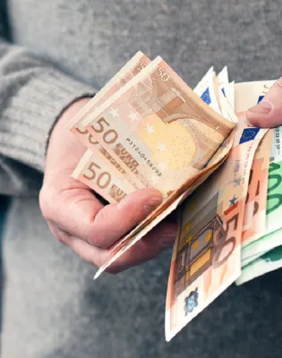 Άνδρας μετράει χρήματα και ευρώ με τα χέρια του