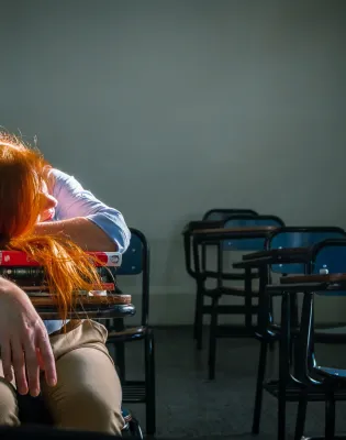 Κουρασμένη δασκάλα έχει ξαπλώσει πάνω σε θρανίο τάξης