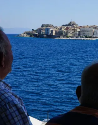 Δύο συνταξιούχοι κάθονται σε παγκάκι και κοιτάζουν τη θάλασσα το καλοκαίρι