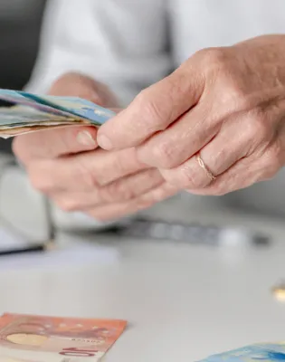 Γυναίκα συνταξιούχους μετράει χρήματα συνταξιοδότησης – αλλαγές στη φορολογία για πρόωρη σύνταξη και ΤΕΑ