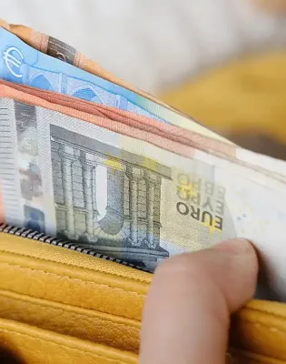 Χέρια ανθρώπου ανοίγουν πορτοφόλι γεμάτο χαρτονομίσματα ευρώ