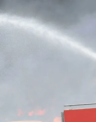 Πυροσβέστης πάνω σε όχημα της Πυροσβεστικής σβήνει με μάνικα φωτιά 