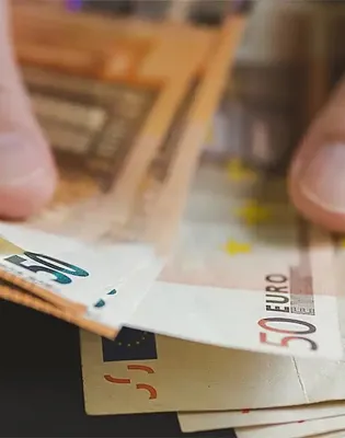 Ανδρικά χέρια που μετρούν χαρτονομίσματα ευρώ, σε άρθρο που αφορά τα ποσά και τις πληρωμές των συντάξεων