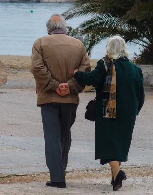Συνταξιούχοι περπατάνε στον δρόμο με φόντο τη θάλασσα