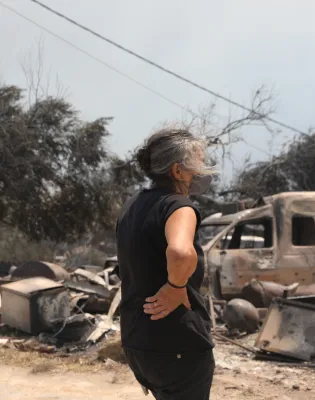 Γυναίκα κοιτάζει τις καταστροφές από τη φωτιά στο Πόρτο Γερμενό