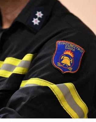 Πυροσβέστης όπου στο μανίκι του έχει λογότυπο της Πυροσβεστικής
