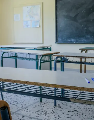 Αίθουσα σχολείου με άδεια θρανία, πίνακα και αντισηπτικό επάνω σε θρανίο