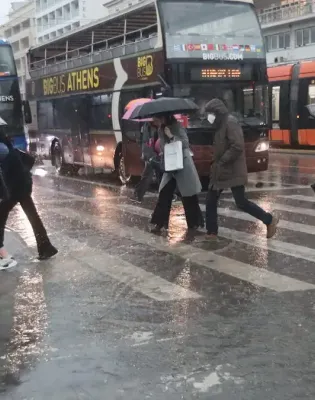 Άνθρωποι με ομπρέλες στον δρόμο τρέχουν από βροχή και κακοκαιρία
