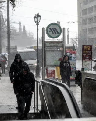 Κόσμος περπατάει μέσα στην κακοκαιρία σε σταθμό του Μετρό στην Αθήνα